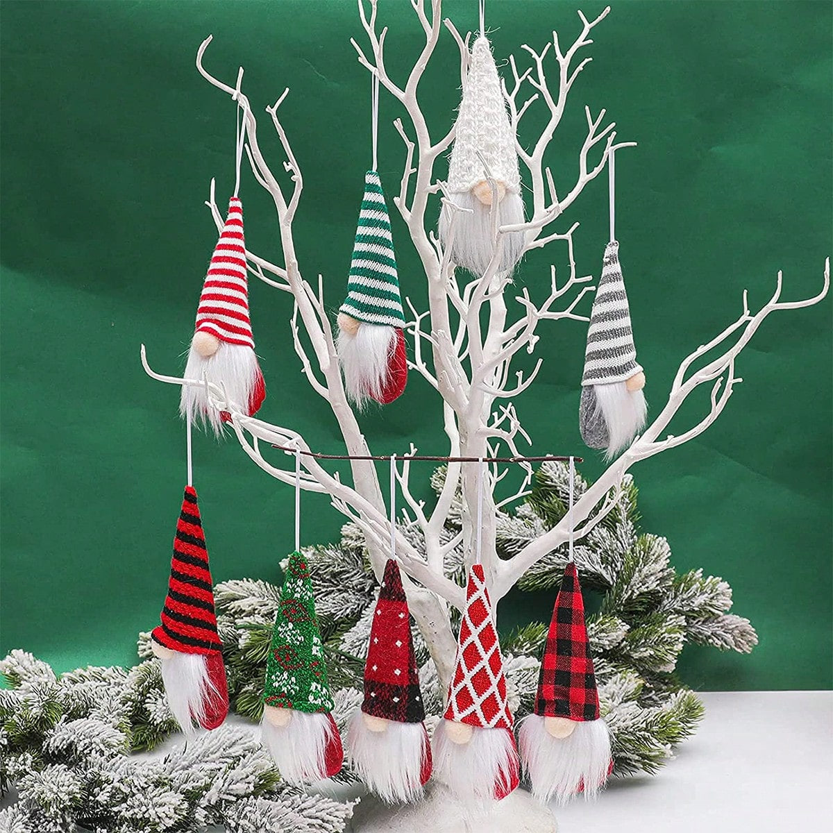 Decorative gnomes hanging from a white branch against a green background
