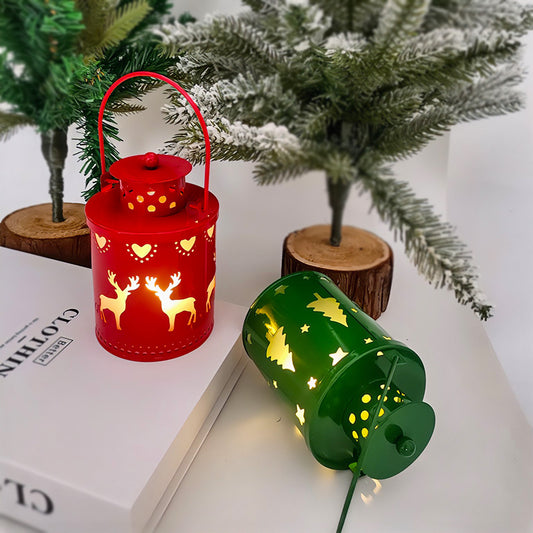 Red and green metal lanterns with decorative cutouts on a white surface with a Christmas tree in the background.