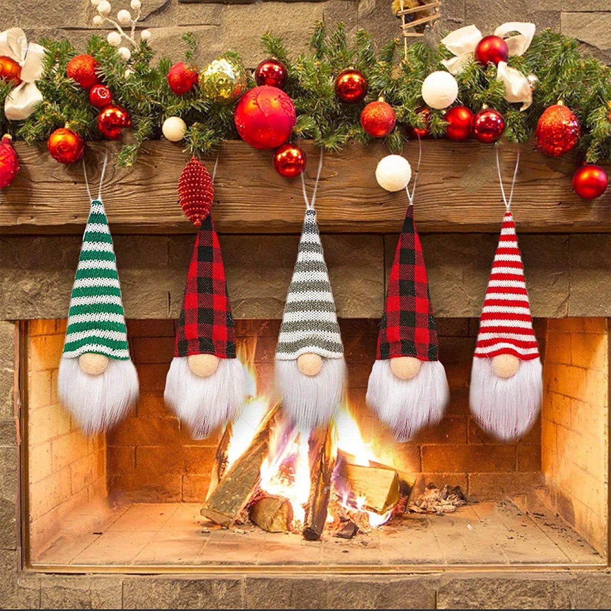 Five gnome ornaments in front of a fireplace with Christmas decorations.