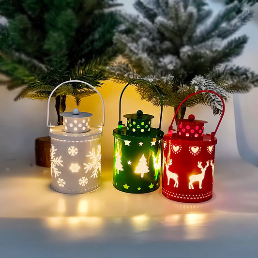 Three decorative lanterns in white, green, and red with Christmas designs, placed against a blurred Christmas tree background.